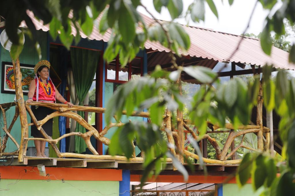 una donna seduta sul balcone di un edificio di POSADA KAUAI a Mocoa