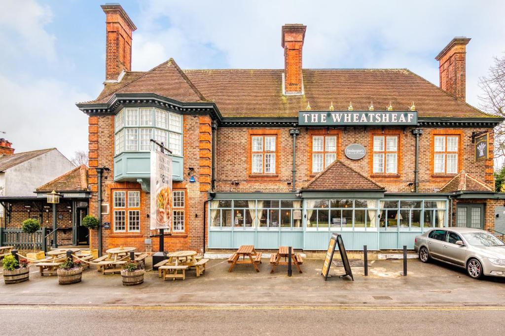 un bâtiment avec des tables et des bancs devant lui dans l'établissement The Wheatsheaf by Innkeeper's Collection, à Woking