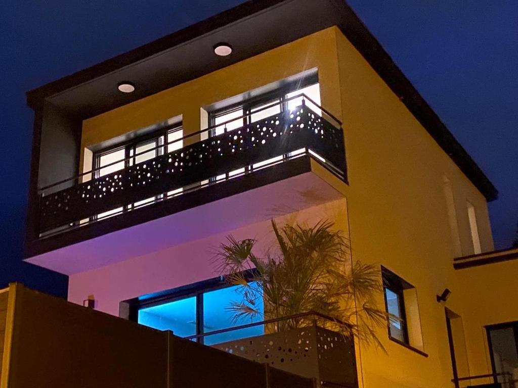 un gran edificio amarillo con balcón por la noche en Grande Villa cosy avec piscine, sauna & jacuzzi en Juvignac