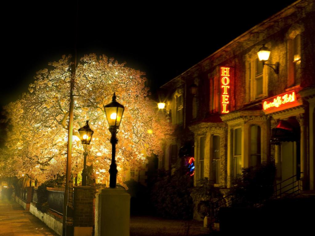 una calle iluminada por la noche con un cartel de neón en Overcliffe Hotel, en Gravesend