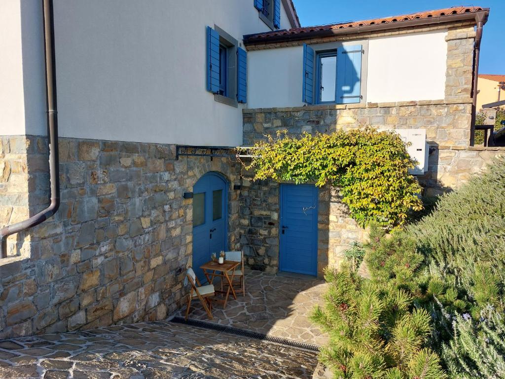 ein Steinhaus mit blauen Türen und einem Tisch in der Unterkunft APARTMENT KORTINE in Sečovlje