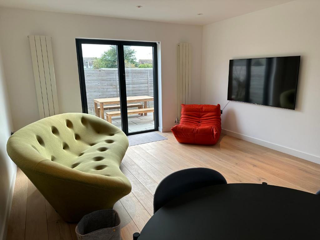 a living room with a chair and a television at ALTIDO Stylish house with patio in Devon in Ipplepen