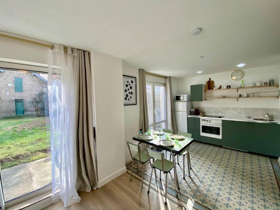 uma cozinha com uma mesa e cadeiras e uma cozinha com uma janela em La Villa des Oiseaux - Coeur de Vichy em Vichy
