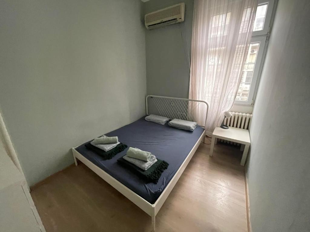 um pequeno quarto com uma cama azul e uma janela em Habitat Hostel em Belgrado