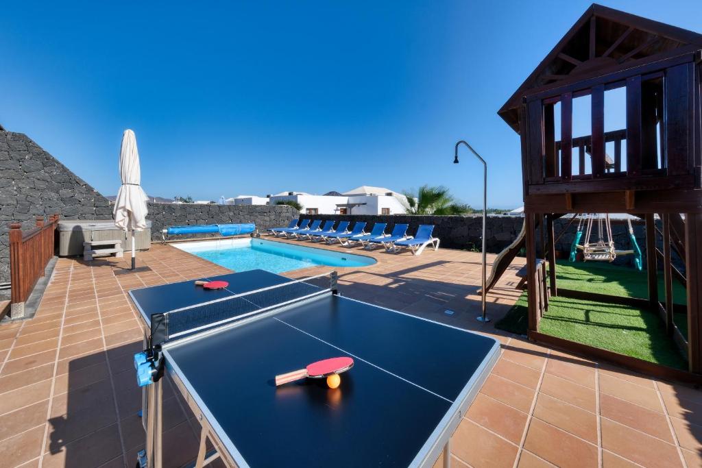 a ping pong table on a patio next to a pool at Villa Flavia-private pool, jacuzzi, sea views in Playa Blanca