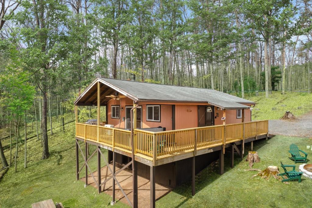 a house with a large deck in the woods at Modern Cabin w Hot Tub, Wifi & Huge Deck! in Hedgesville