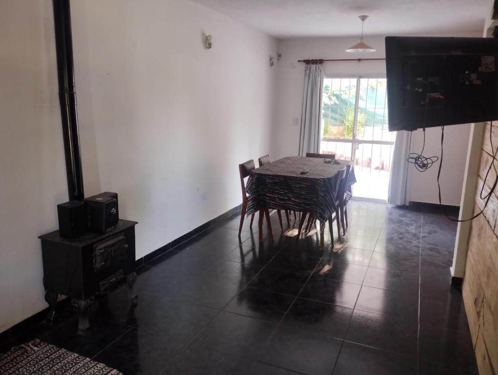 comedor con mesa, sillas y TV en Casa Estancia Vieja en Villa Carlos Paz