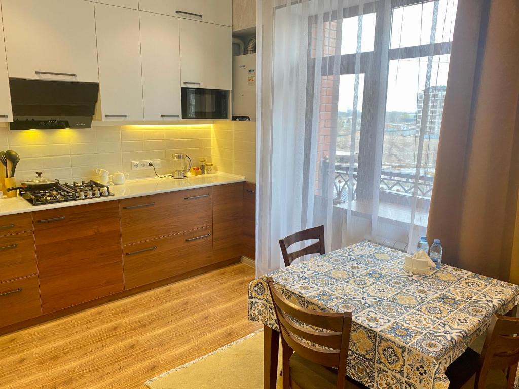 uma cozinha com uma mesa e uma cozinha com uma janela em Spacious Apartment in New Building, Near the City Center and Airport em Tashkent