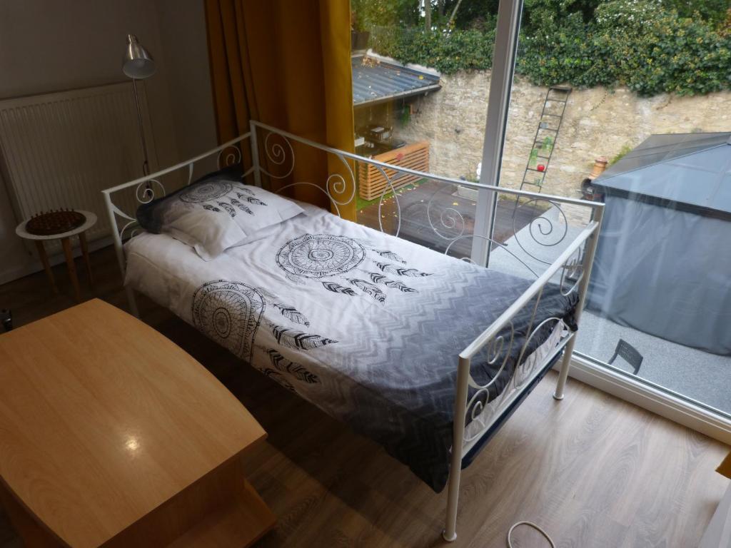 ein kleines Bett in einem Zimmer mit Fenster in der Unterkunft T2 calme et chaleureux 1 à 5 pers in Alençon