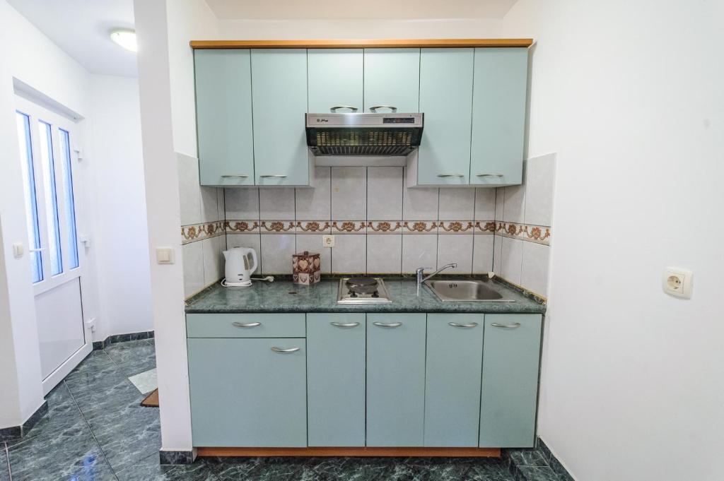 a kitchen with blue cabinets and a sink at Apartments & rooms Lucie in Posedarje