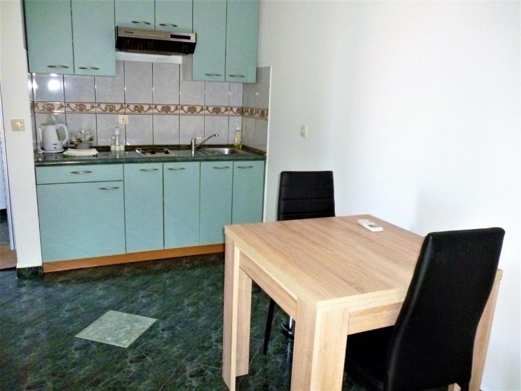 a kitchen with blue cabinets and a wooden table and chairs at Apartments & rooms Lucie in Posedarje
