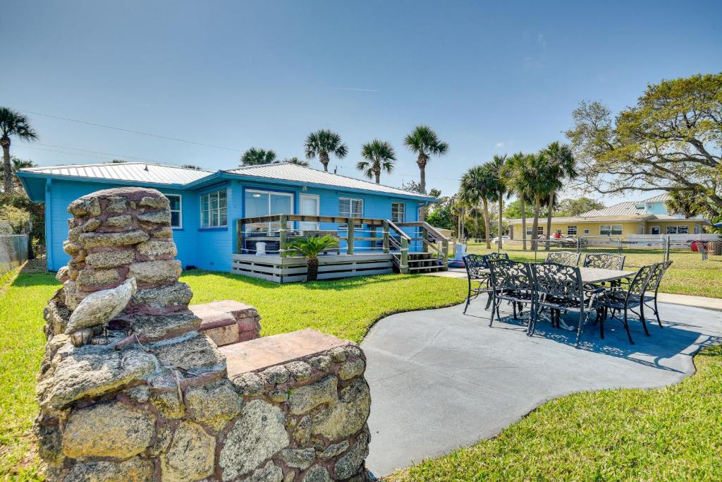 a blue house with a stone wall and a table and chairs at Riverfront Port Orange Home with Dock and Slip! in Port Orange