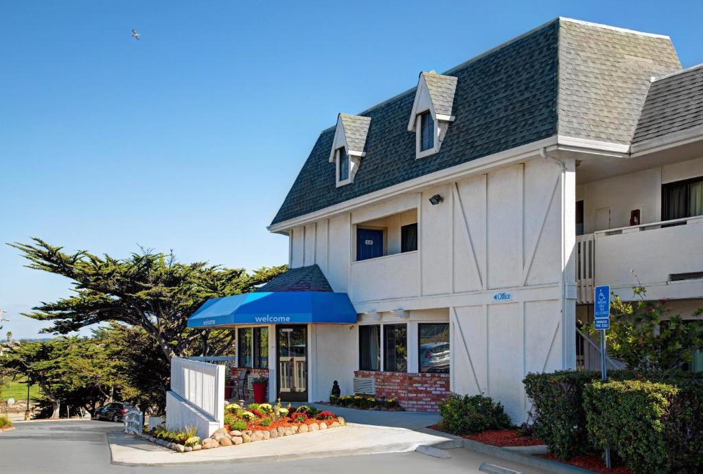 a white building with a blue umbrella in front of it at Motel 6-Marina, CA - Monterey in Marina