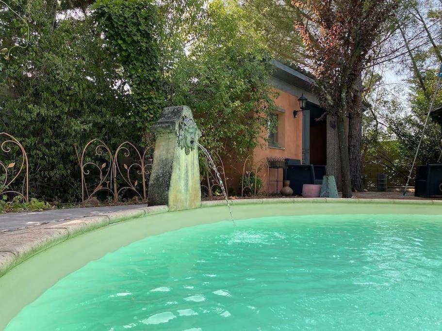 a pool with a water fountain in front of a house at Cottage chaleureux avec piscine privée in Sainte Anastasie - Aubarne