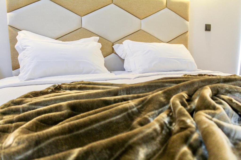 an unmade bed with a brown blanket and white pillows at Hostel Pia do Urso in Batalha