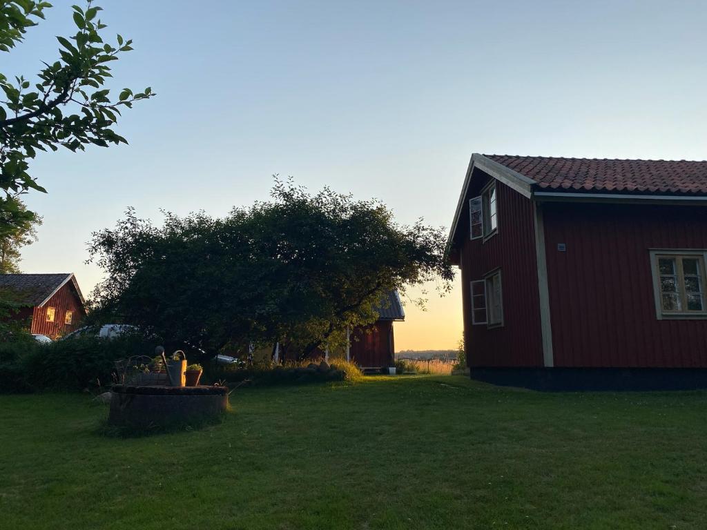 uma casa vermelha com uma fonte no quintal em Änden på Säby Tjörn em Säby