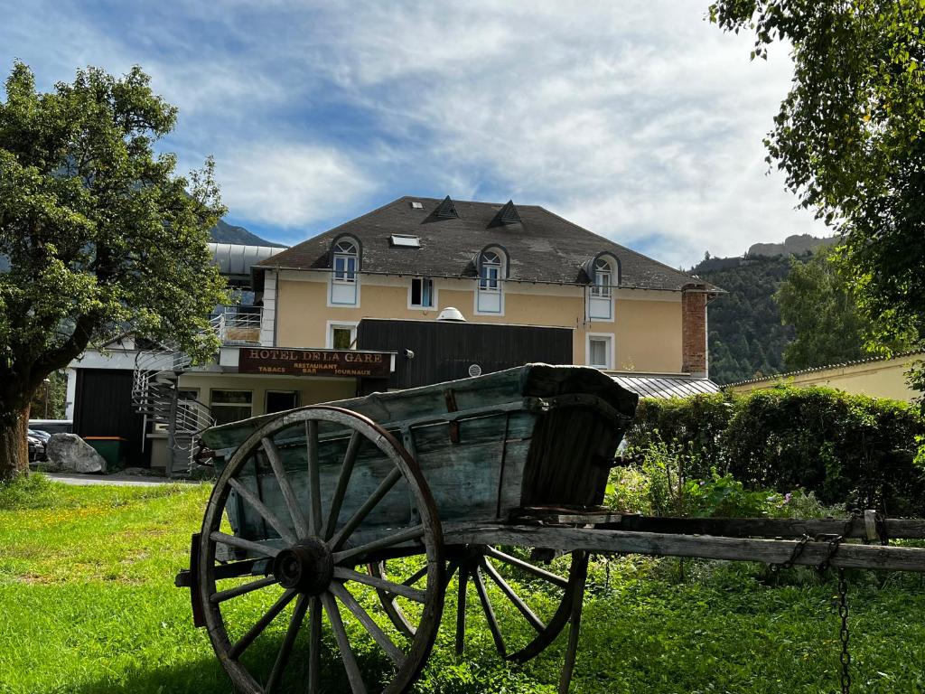 une charrette en bois assise dans l'herbe devant une maison dans l'établissement HOTEL DE LA GARE, à Eygliers
