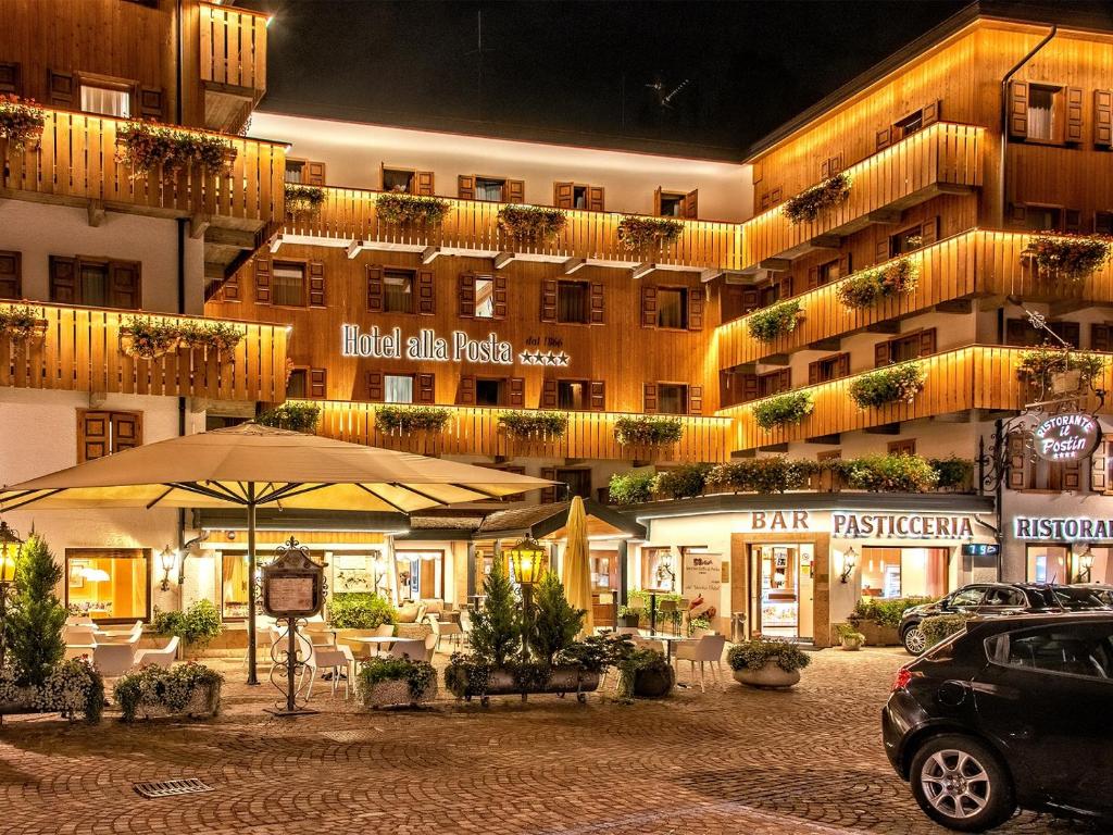 a hotel building with an umbrella and a parking lot at Hotel Alla Posta in Alleghe