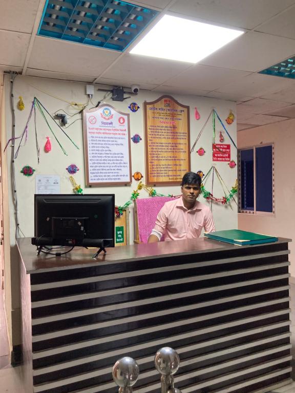 a man standing behind a counter in a room at Hotel Shahin Residential Jatrabari in Dhaka