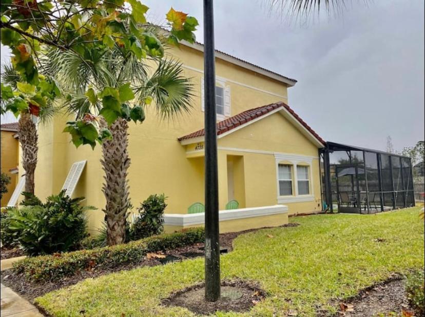 a yellow house with a palm tree in front of it at Terra Verde Resort in Kissimmee