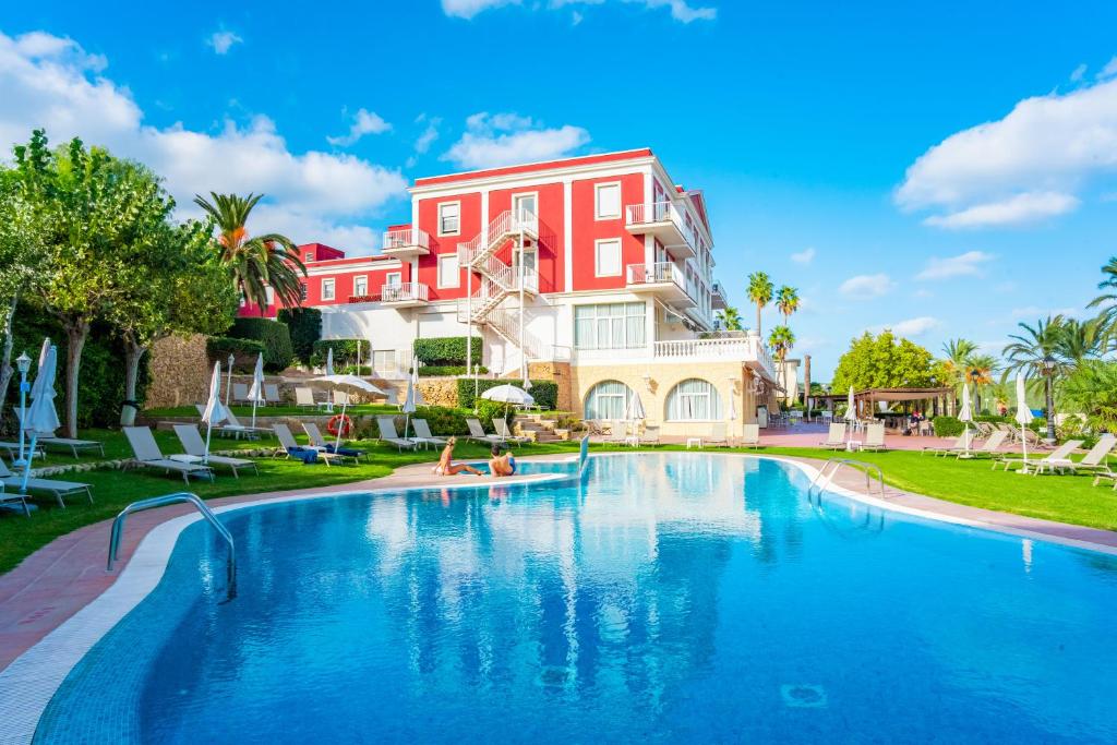 a large swimming pool in front of a red building at Seth Port Mahón in Mahón