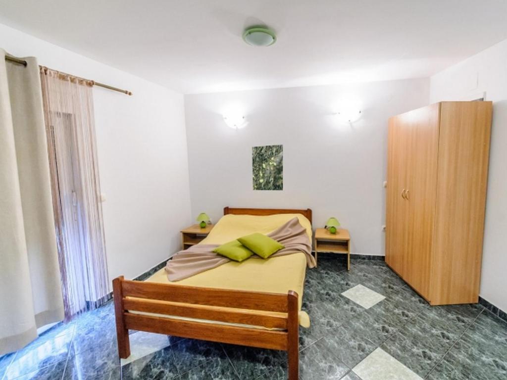 a bedroom with a bed and a wooden cabinet at Apartments & rooms Lucie in Posedarje
