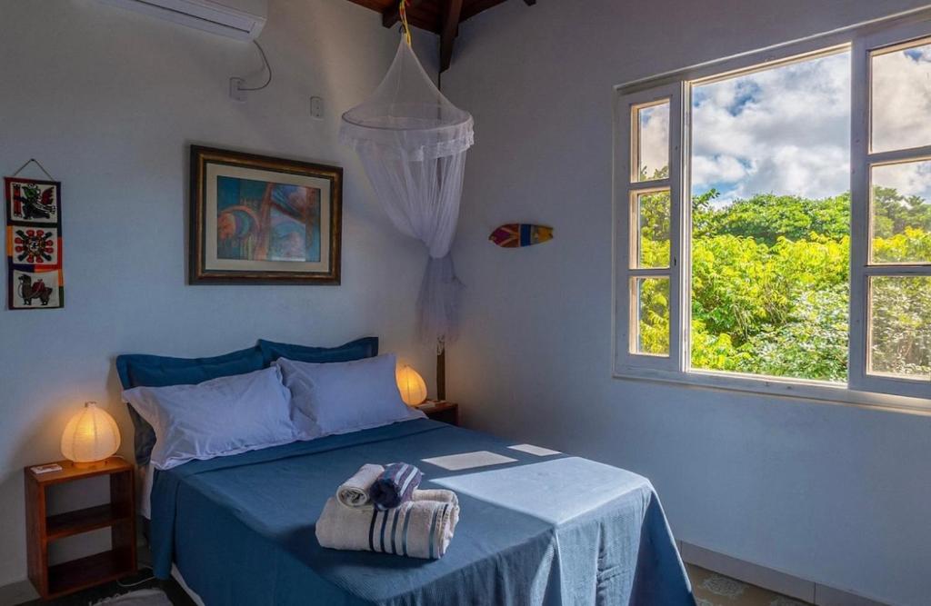 a bedroom with a blue bed and two windows at Casa Boomerang in Marau