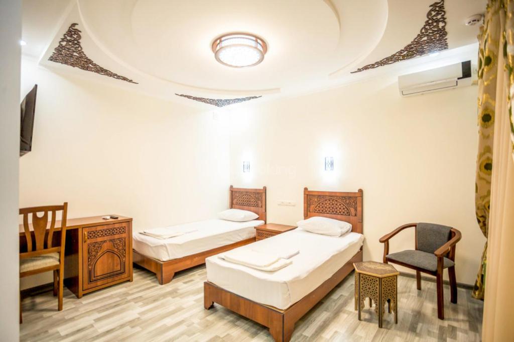 a room with two beds and a table and chairs at AYUB Boutique Hotel in Bukhara