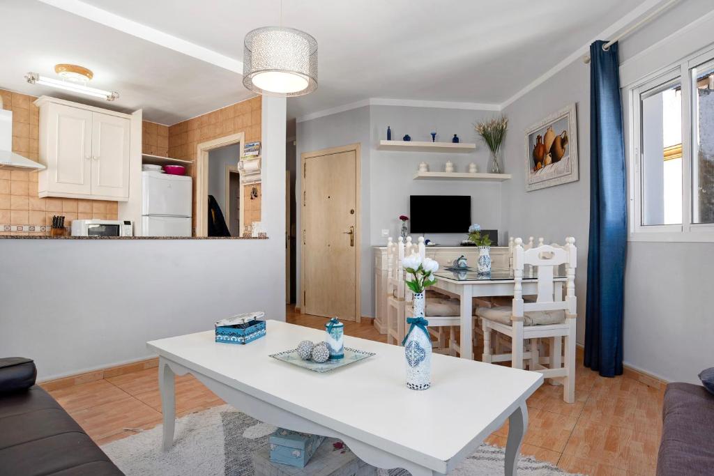 a living room with a white table and a kitchen at Apartamento Goya in Conil de la Frontera