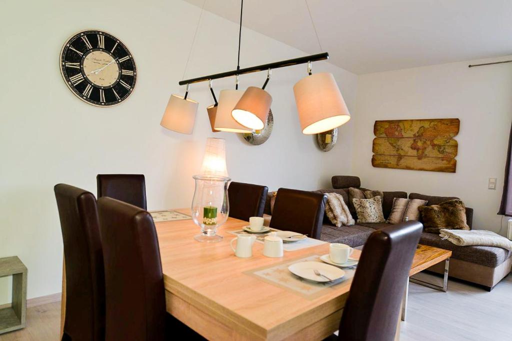 een eettafel met stoelen en een klok aan de muur bij Haus Frauenpreiss F502 in Cuxhaven
