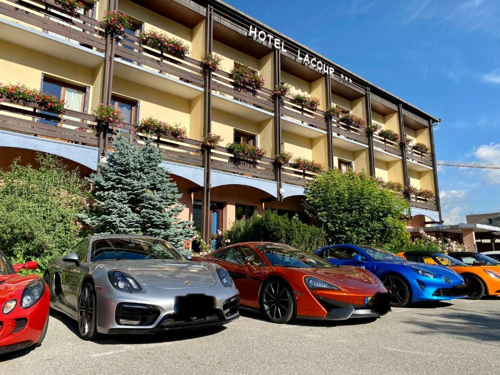 a row of cars parked in front of a building at Hôtel Lacour in Eygliers