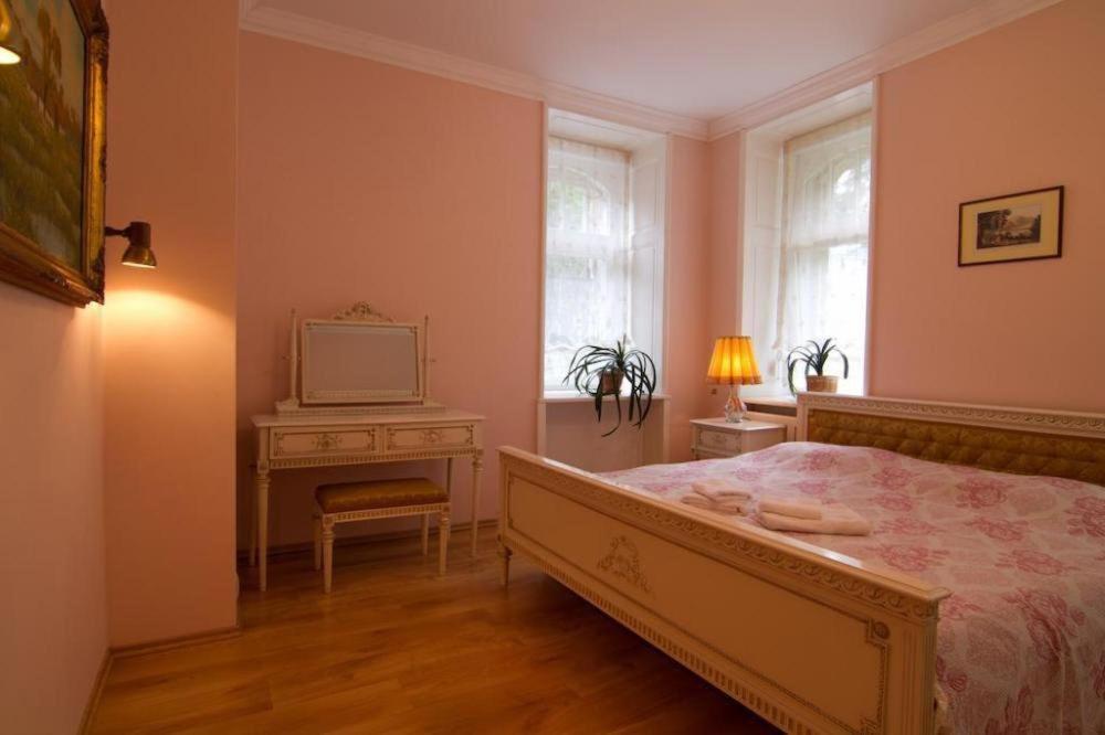 1 dormitorio con 1 cama y mesa con TV en Apartmány vila Liberty en Karlovy Vary