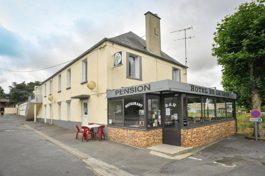 un restaurant avec des chaises rouges en face d'un bâtiment dans l'établissement Hôtel et Restaurant de la Gare Torigny-les-Villes, à Torigni-sur-Vire