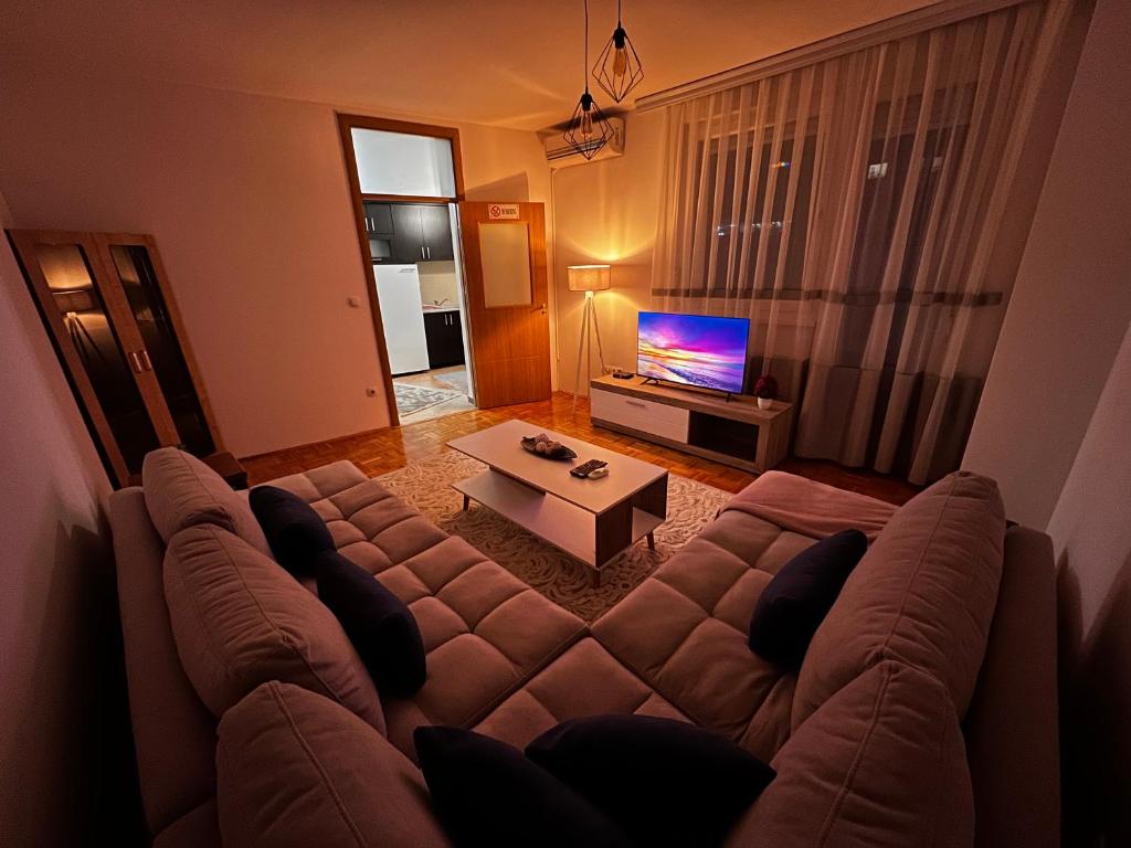 - un salon avec un grand canapé et une télévision dans l'établissement Sunrise Apartment in Prishtina, Kosovo, à Pristina