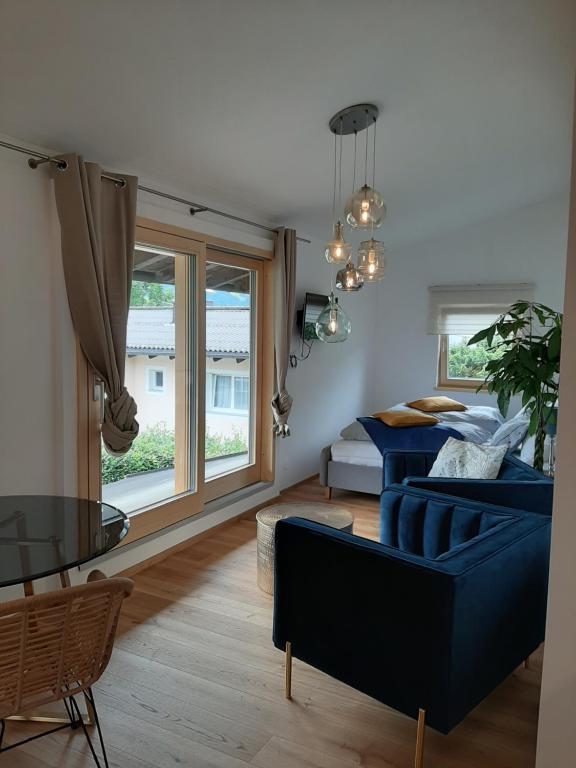 uma sala de estar com um sofá azul e uma cama em Studio mit großer Loggia em Saalfelden am Steinernen Meer