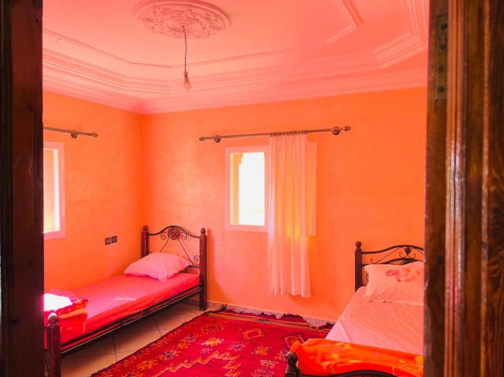 two beds in a room with orange walls at appartement Ocean in Tamraght Ouzdar