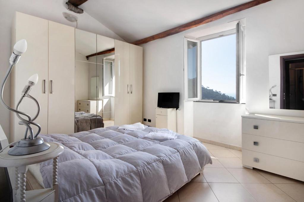 a white bedroom with a large bed and a window at Bilocale Serra in Bonassola