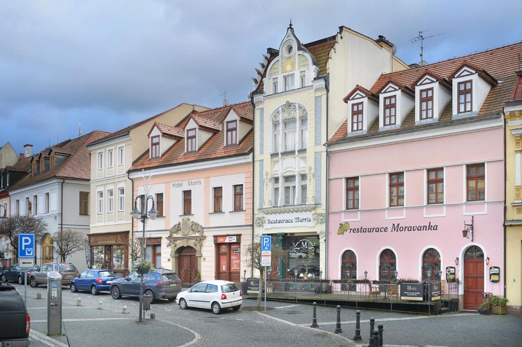 un grupo de edificios en una calle con coches aparcados en City Hotel Morris en Česká Lípa