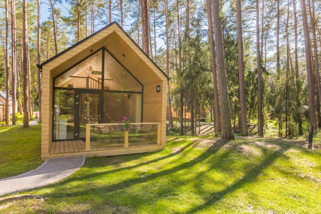 ein winziges Haus im Wald mit einem großen Fenster in der Unterkunft BURSZTYNOWO Ośrodek Wczasowy in Sztutowo