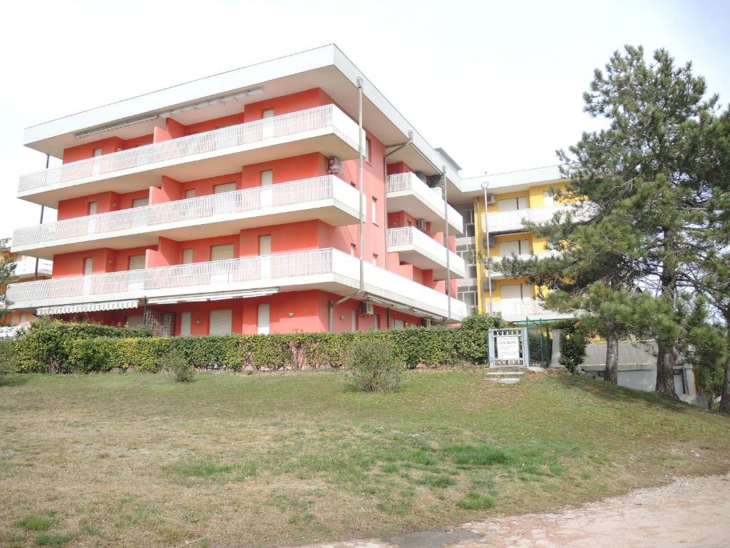 czerwony apartamentowiec z trawnikiem przed nim w obiekcie Condominio Biloba w Bibione