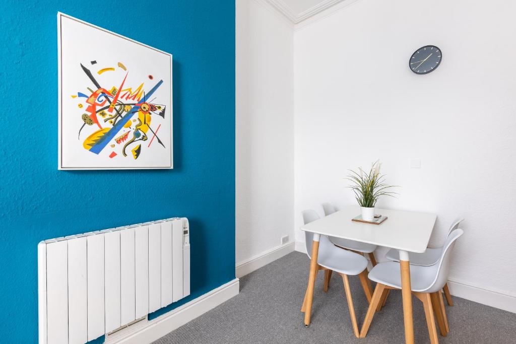 a dining room with a white table and a blue wall at Judah Suites by Koya Homes - TV Bed Apartment, Central High Street, Free Parking in Barry