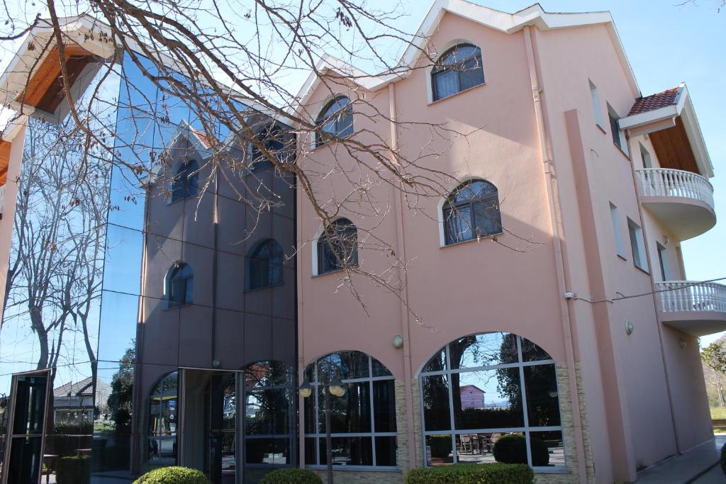 a pink building with arched windows at Hotel Hasmegaj in Mjedë