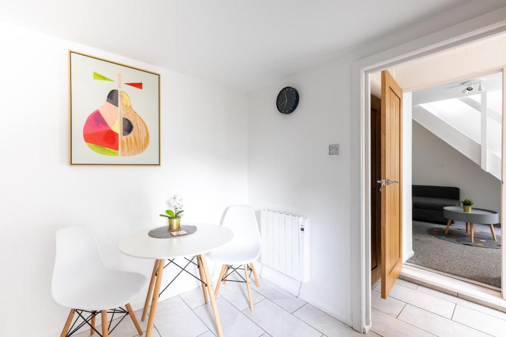 a white dining room with a white table and white chairs at Judah Suites by Koya Homes - TV Bed Apartment, Central High Street, Free Parking in Barry
