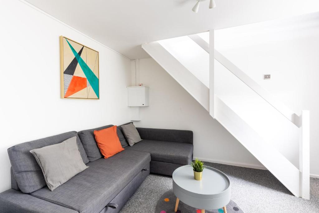 a living room with a couch and a staircase at Judah Suites by Koya Homes - TV Bed Apartment, Central High Street, Free Parking in Barry