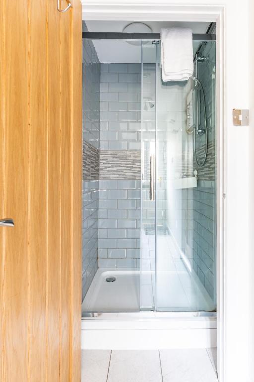 a shower with a glass door in a bathroom at Judah Suites by Koya Homes - TV Bed Apartment, Central High Street, Free Parking in Barry