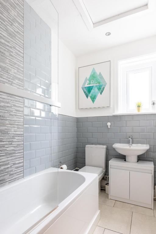 a white bathroom with a tub and a sink at Judah Suites by Koya Homes - TV Bed Apartment, Central High Street, Free Parking in Barry