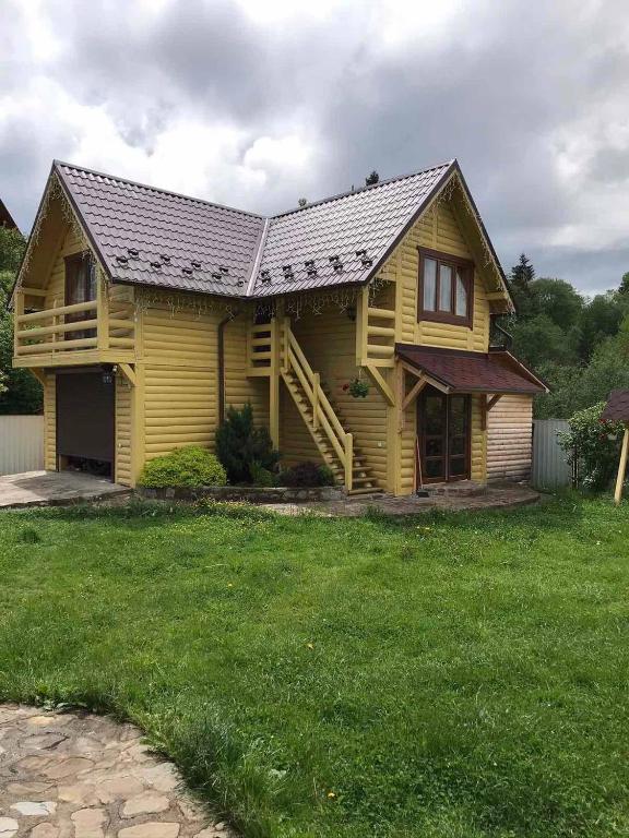 una casa amarilla con techo de metal en un patio en Модрина, en Vorokhta