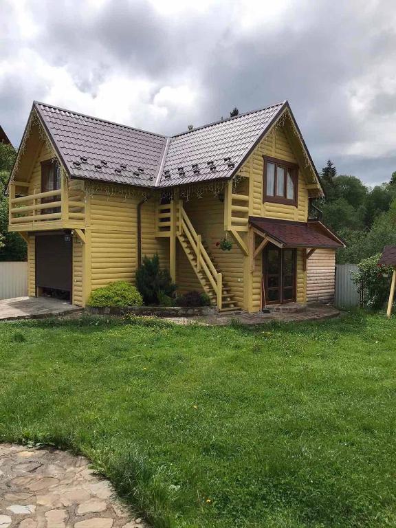 a yellow house with a metal roof on a yard at Модрина in Vorokhta