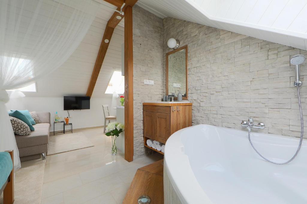 a bathroom with a tub and a living room at Lotti Residence Romantik in Balatonfüred