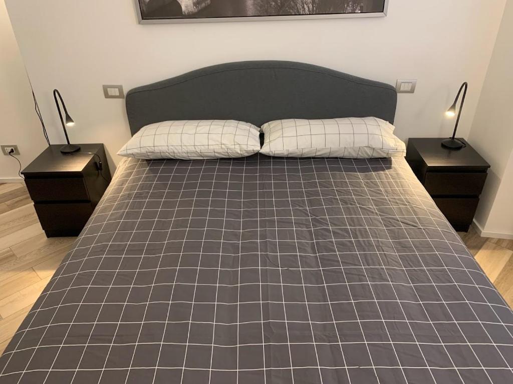 ein Schlafzimmer mit einem Bett mit zwei Nachttischen und zwei Lampen in der Unterkunft ANDREA in Mailand